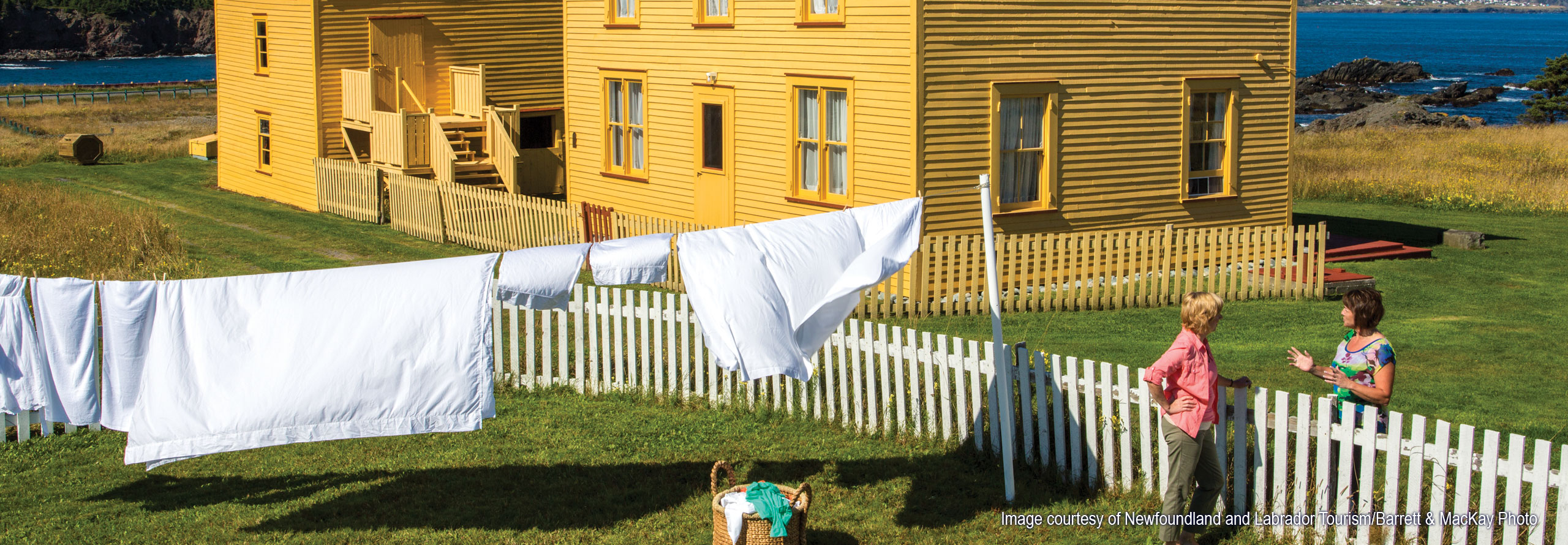 Image courtesy of Newfoundland and Labrador Tourism and Barrett & MacKay Photo Two women talking at a fence